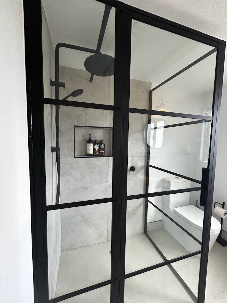 Matte black framed shower screen and floor-to-ceiling tiling on a recent ensuite rebuild