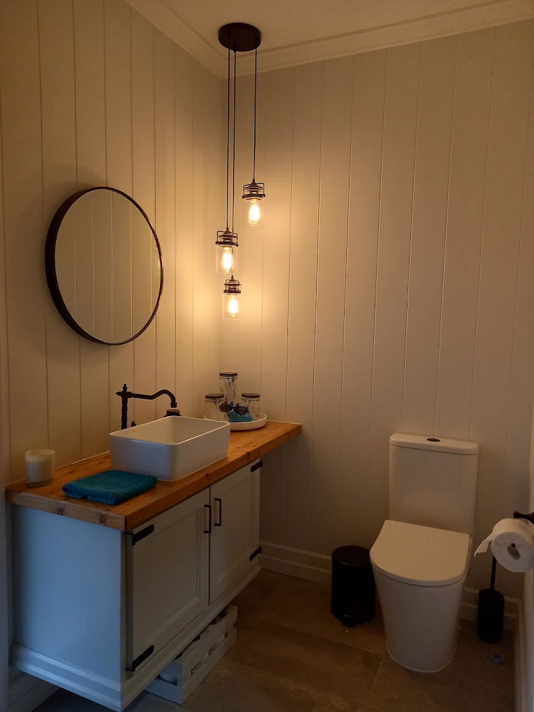 Timber-topped vanity and pendant lighting in a completed powder room renovation